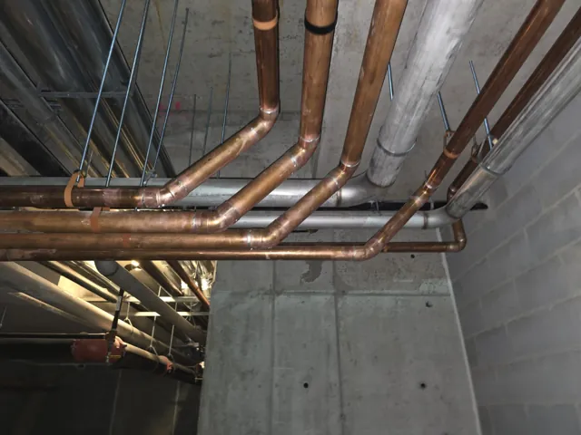 Copper pipe bends and fittings at a ceiling installation