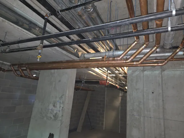 Parallel copper pipe routes beneath a concrete ceiling