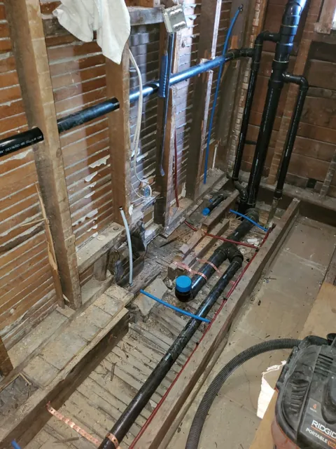 Water distribution piping in an open service wall